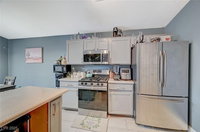 kitchen featuring stainless steel appliances, light tile patterned floors, and white cabinets