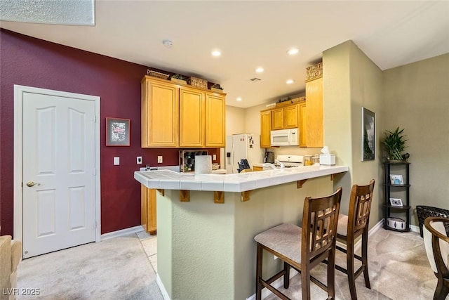 kitchen with kitchen peninsula, a breakfast bar area, light carpet, and tile counters