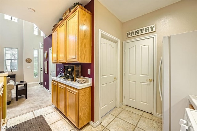 kitchen with light tile patterned floors, white fridge, and lofted ceiling