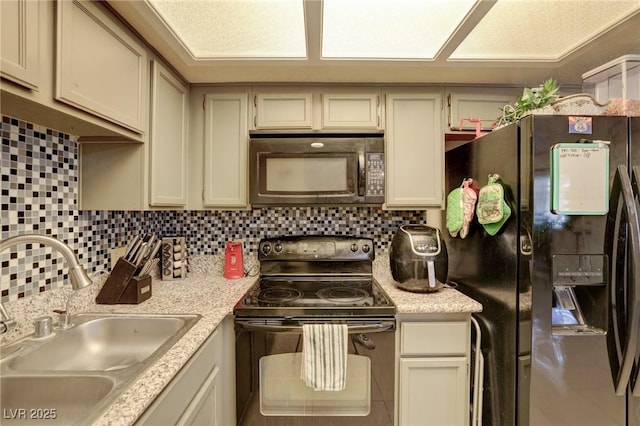 kitchen featuring black appliances, cream cabinetry, backsplash, and sink