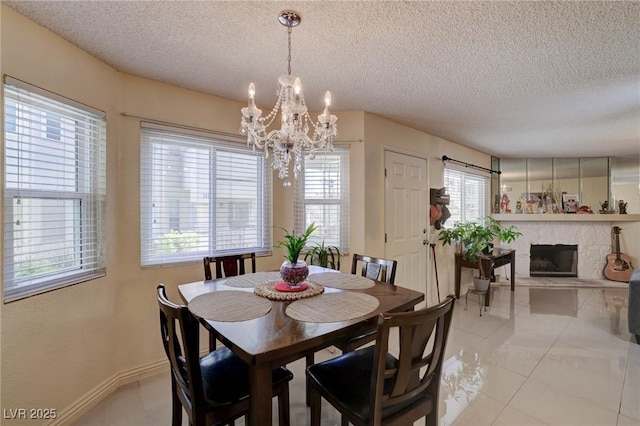 tiled dining room featuring a textured ceiling, an inviting chandelier, and a fireplace