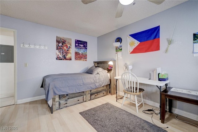 bedroom with ceiling fan, a textured ceiling, electric panel, and wood-type flooring