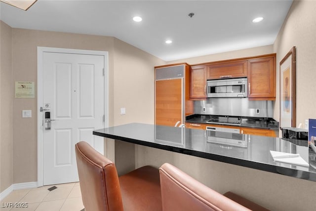 kitchen with black electric stovetop, paneled fridge, and light tile patterned floors