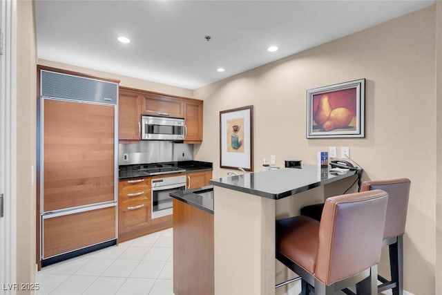 kitchen featuring sink, a breakfast bar, kitchen peninsula, and appliances with stainless steel finishes