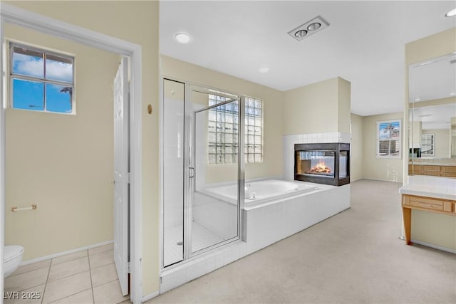 full bathroom featuring toilet, separate shower and tub, a multi sided fireplace, vanity, and tile patterned flooring