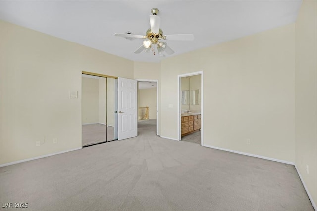 unfurnished bedroom with connected bathroom, light colored carpet, a closet, and ceiling fan