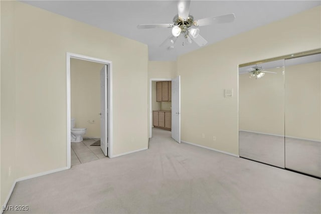 unfurnished bedroom with connected bathroom, light carpet, ceiling fan, and a closet