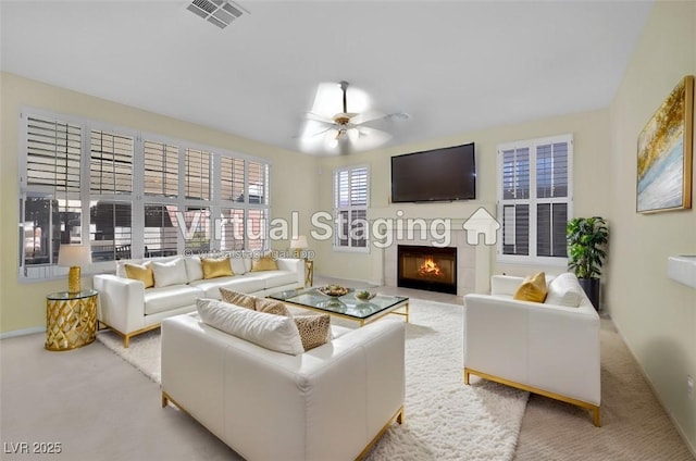 living room with ceiling fan, light carpet, and a tile fireplace