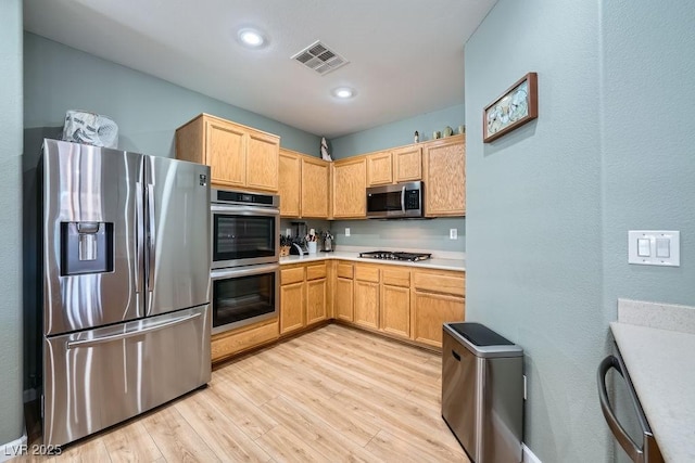 kitchen featuring light brown cabinetry, stainless steel appliances, and light wood-type flooring