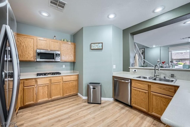 kitchen featuring kitchen peninsula, sink, stainless steel appliances, and light hardwood / wood-style floors