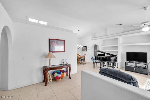 living room featuring built in shelves, vaulted ceiling, light tile patterned flooring, and ceiling fan with notable chandelier