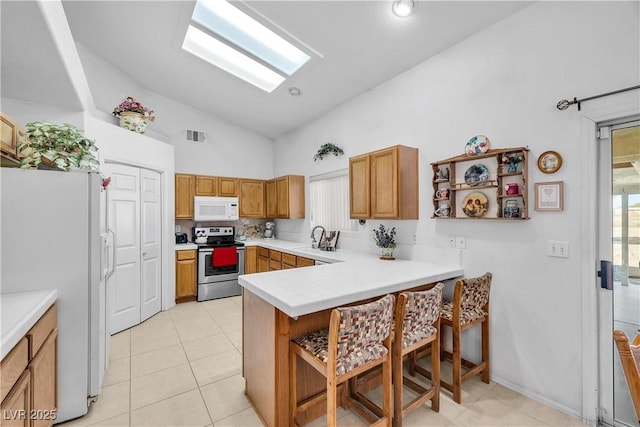 kitchen with kitchen peninsula, white appliances, a kitchen breakfast bar, light tile patterned flooring, and sink