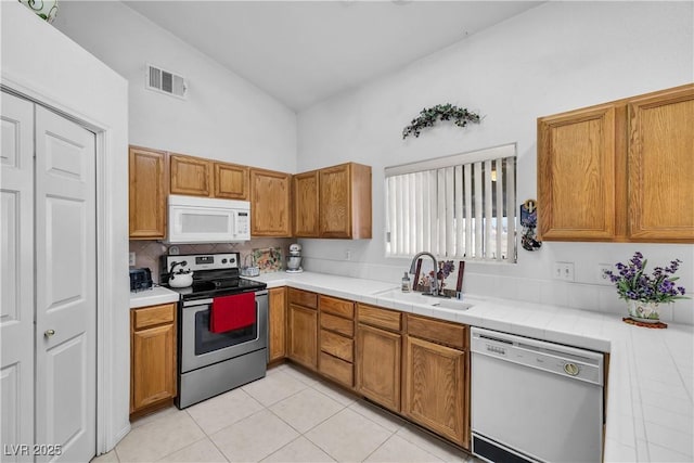 kitchen featuring light tile patterned flooring, tile countertops, sink, and white appliances