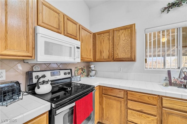 kitchen featuring tile countertops, decorative backsplash, electric range, and sink