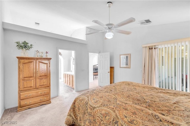 bedroom featuring ceiling fan, light carpet, vaulted ceiling, and connected bathroom