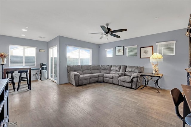 living room with ceiling fan, plenty of natural light, and light hardwood / wood-style floors