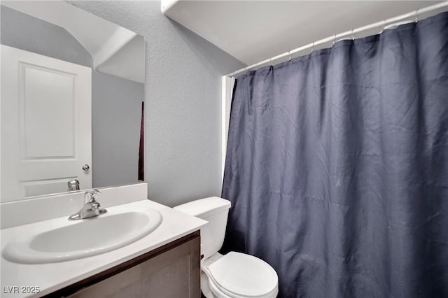 bathroom with curtained shower, toilet, vanity, and vaulted ceiling