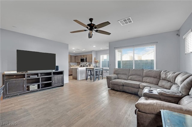 living room featuring ceiling fan and light hardwood / wood-style flooring