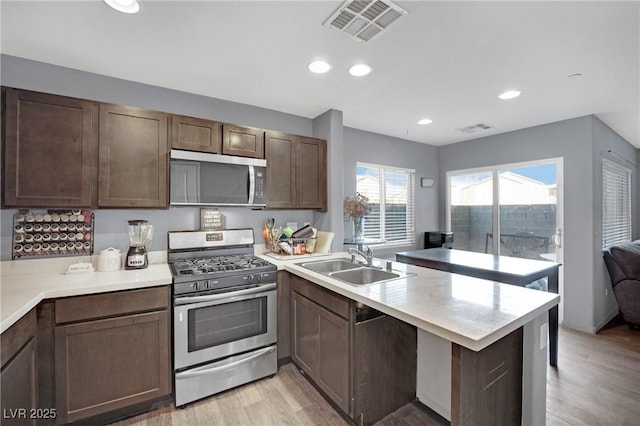 kitchen featuring kitchen peninsula, sink, light hardwood / wood-style flooring, stainless steel appliances, and dark brown cabinets