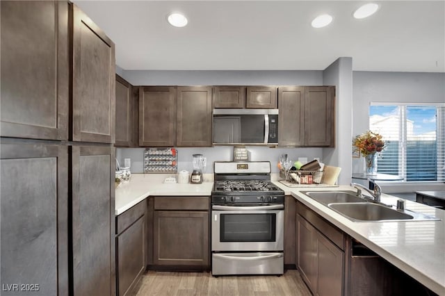 kitchen with light hardwood / wood-style floors, sink, dark brown cabinetry, and stainless steel appliances