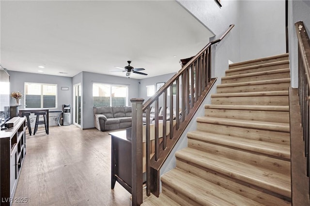 stairs featuring ceiling fan and wood-type flooring