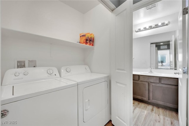 laundry area with light hardwood / wood-style floors, sink, and independent washer and dryer