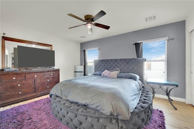 bedroom with ceiling fan, multiple windows, and light hardwood / wood-style floors