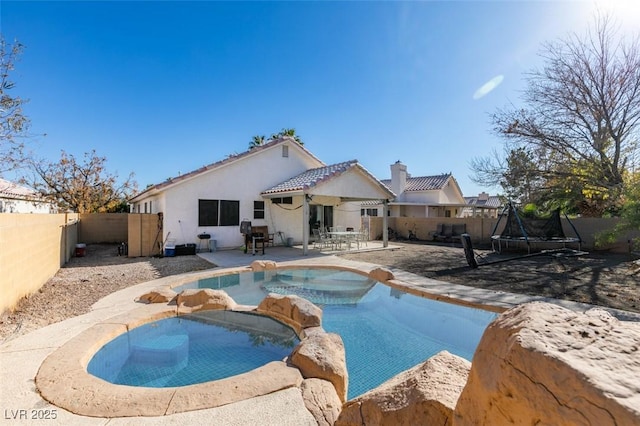 view of swimming pool featuring an in ground hot tub, a patio area, and a trampoline