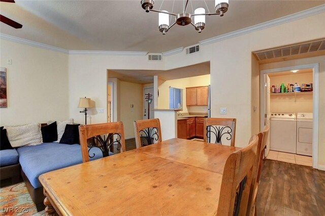 dining room featuring ceiling fan with notable chandelier, hardwood / wood-style floors, crown molding, and washing machine and clothes dryer