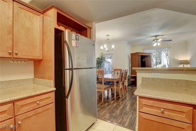 kitchen featuring decorative light fixtures, stainless steel refrigerator, light tile patterned flooring, ornamental molding, and ceiling fan with notable chandelier