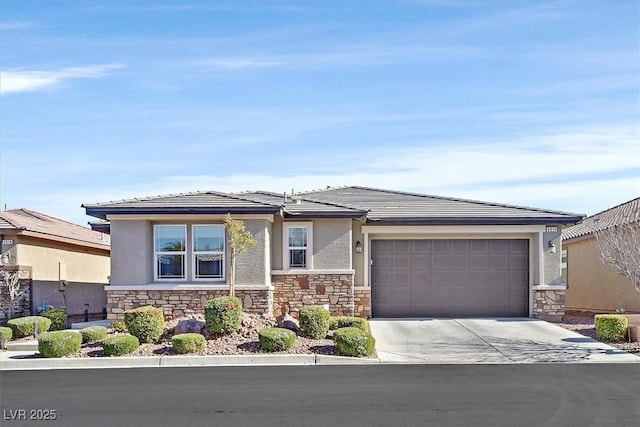 prairie-style home featuring an attached garage, stone siding, concrete driveway, and stucco siding