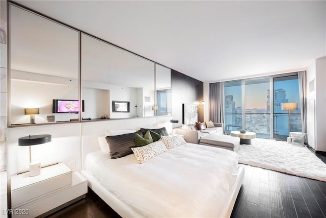 bedroom featuring wood-type flooring, a wall of windows, and access to outside