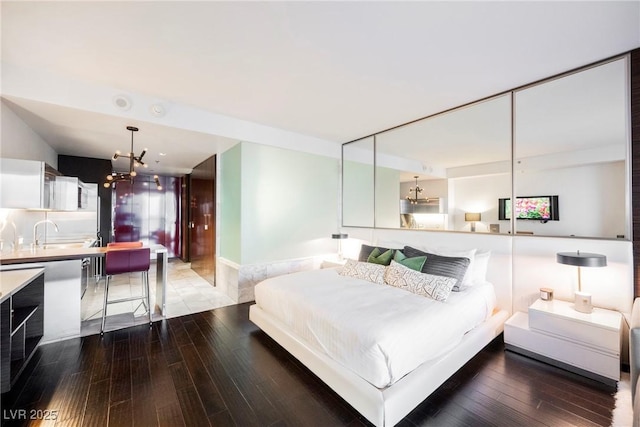 bedroom with hardwood / wood-style flooring, sink, and a notable chandelier