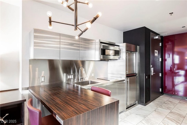 kitchen featuring an inviting chandelier, appliances with stainless steel finishes, tasteful backsplash, stainless steel counters, and sink