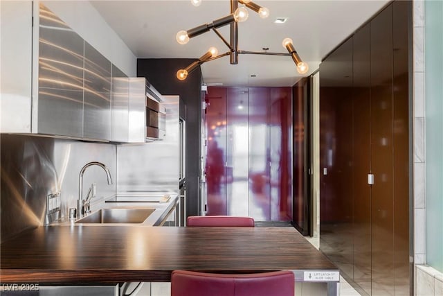 kitchen with sink, kitchen peninsula, a notable chandelier, and tasteful backsplash