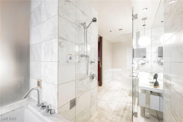 bathroom featuring a shower with door and sink