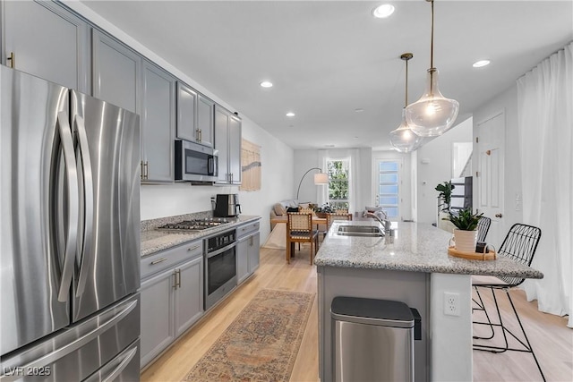 kitchen featuring pendant lighting, a kitchen bar, sink, a kitchen island with sink, and stainless steel appliances