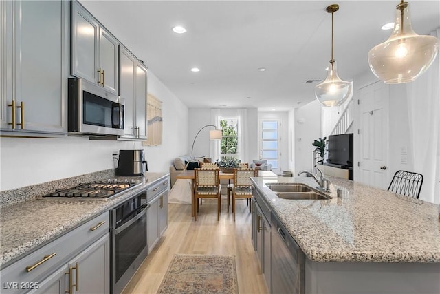 kitchen with sink, hanging light fixtures, a center island with sink, and stainless steel appliances