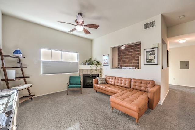 carpeted living room with ceiling fan and a tiled fireplace