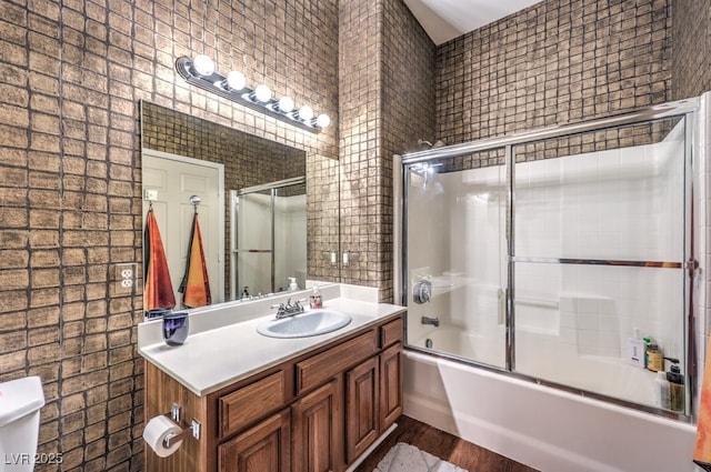 full bathroom with hardwood / wood-style flooring, bath / shower combo with glass door, toilet, and vanity