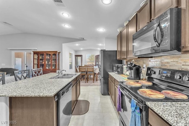 kitchen with black appliances, lofted ceiling, sink, backsplash, and a center island with sink