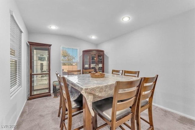 dining area featuring light colored carpet and lofted ceiling