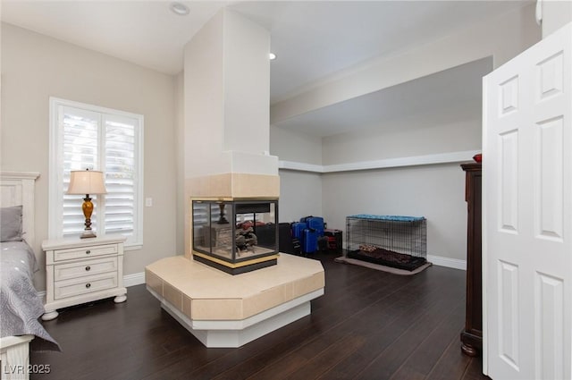 bedroom with dark hardwood / wood-style floors and a tile fireplace