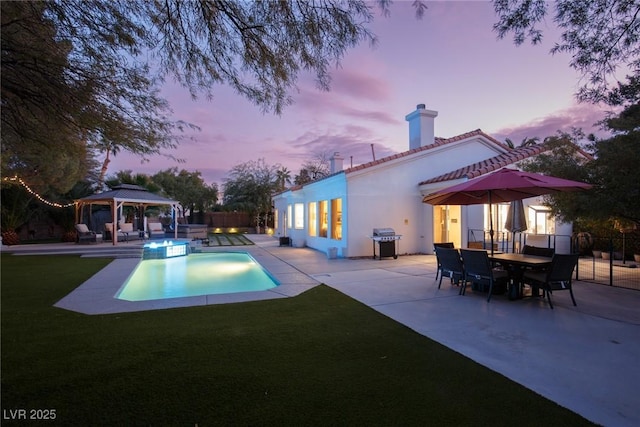 pool at dusk featuring a gazebo, grilling area, a patio area, and a lawn