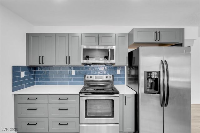 kitchen with gray cabinets, stainless steel appliances, and tasteful backsplash