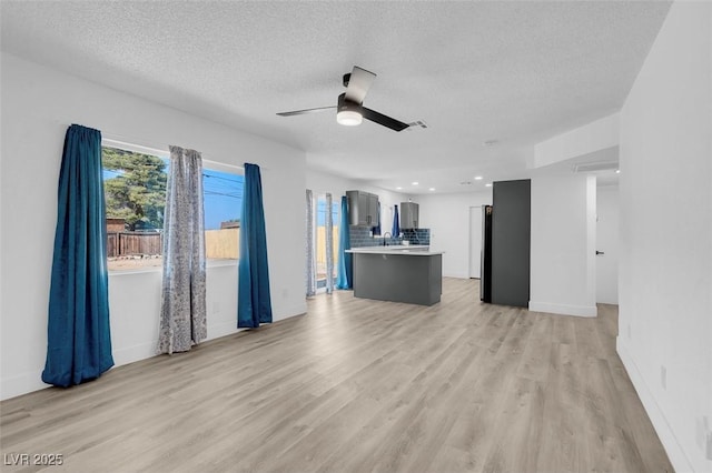 unfurnished living room featuring a textured ceiling, ceiling fan, and light hardwood / wood-style floors