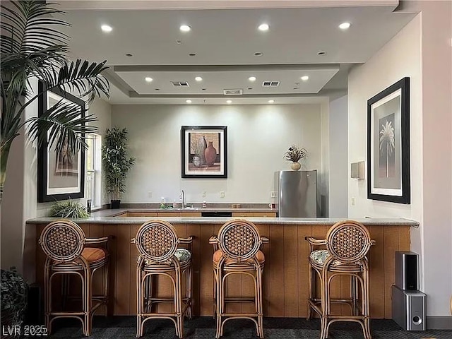 bar with dark colored carpet, sink, and stainless steel refrigerator