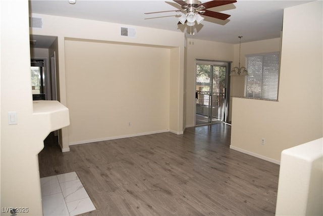 spare room with ceiling fan with notable chandelier and dark hardwood / wood-style floors