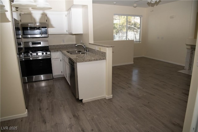 kitchen featuring light stone countertops, white cabinets, appliances with stainless steel finishes, sink, and kitchen peninsula