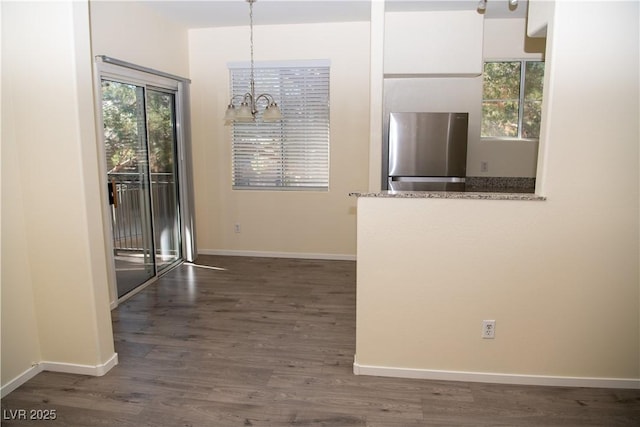 interior space with an inviting chandelier, white cabinetry, dark hardwood / wood-style flooring, stainless steel refrigerator, and pendant lighting